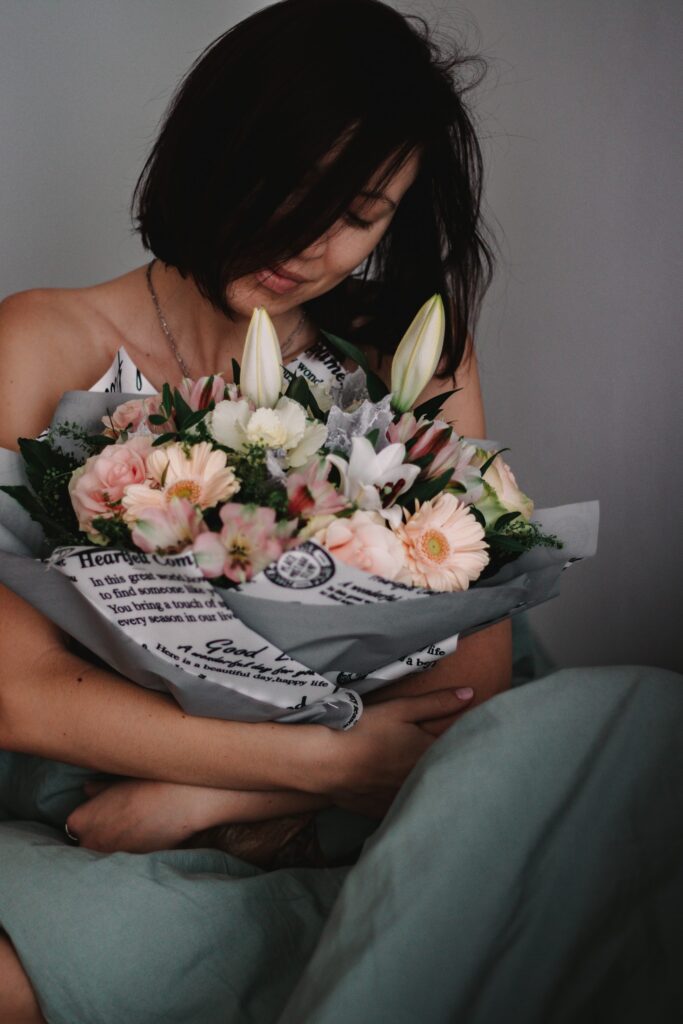 woman in white tube top holding bouquet of flowers