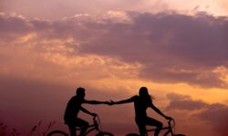 woman on bike reaching for man's hand behind her also on bike