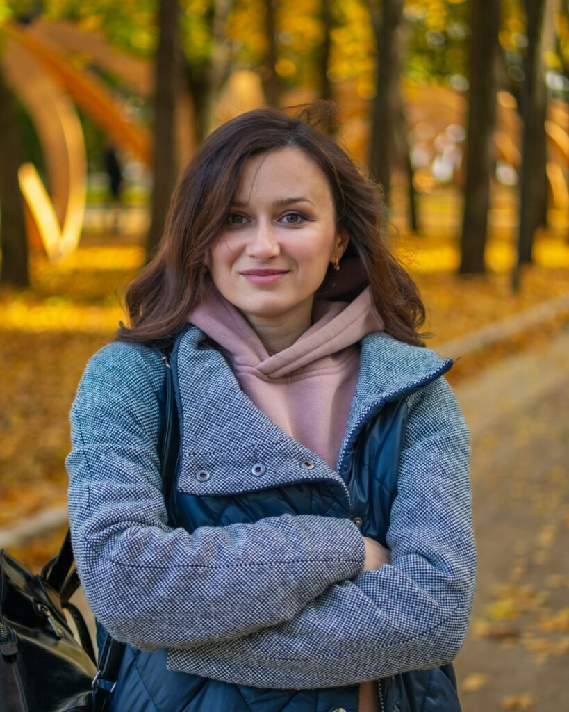a woman standing in a park with her arms crossed