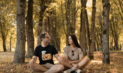 a man and a woman sitting on the ground in a forest