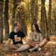 a man and a woman sitting on the ground in a forest